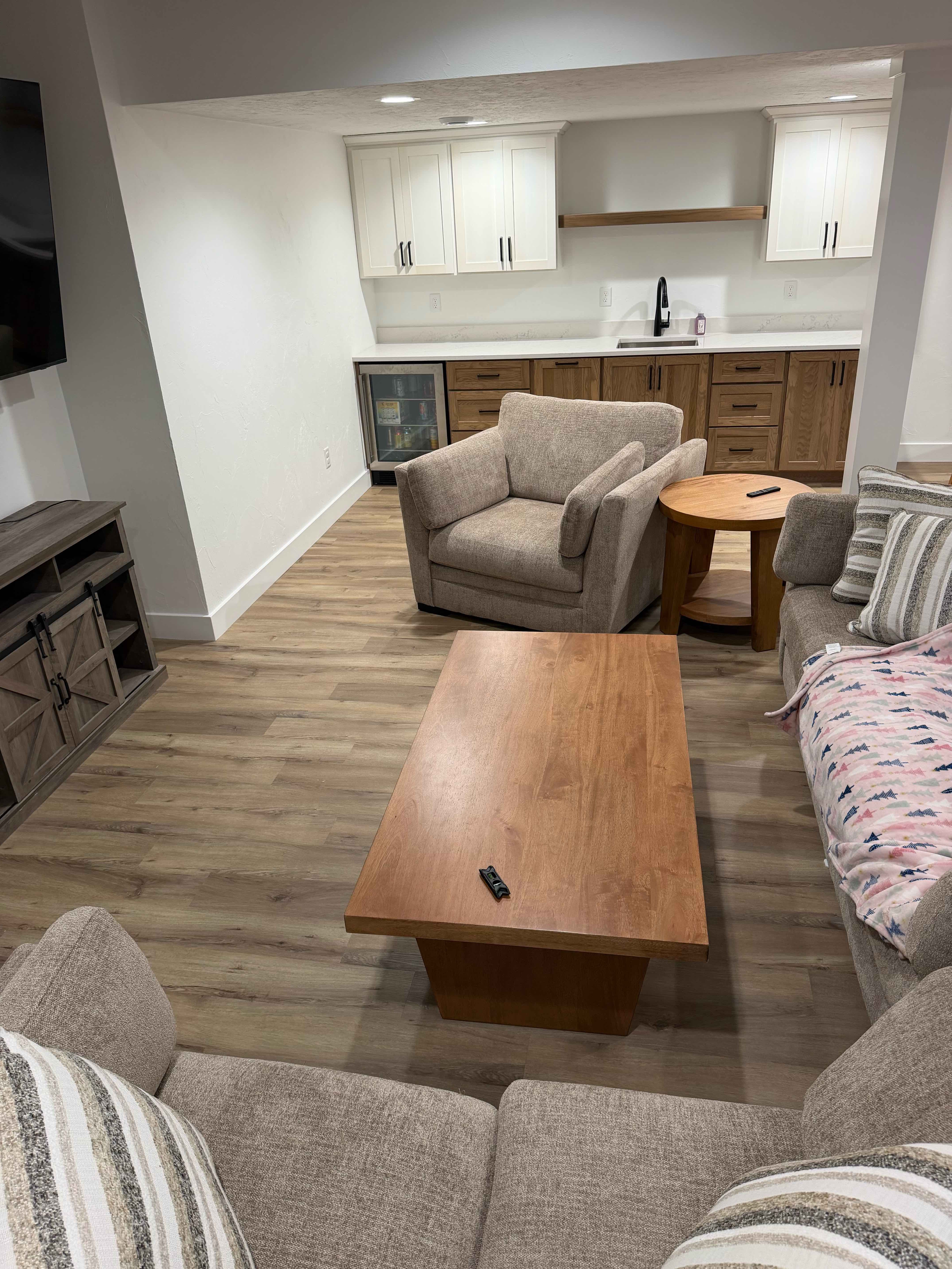 Finished basement family room with luxury vinyl plank flooring, custom wet bar, and recessed lighting built by ARP Building Services in Mid-Michigan