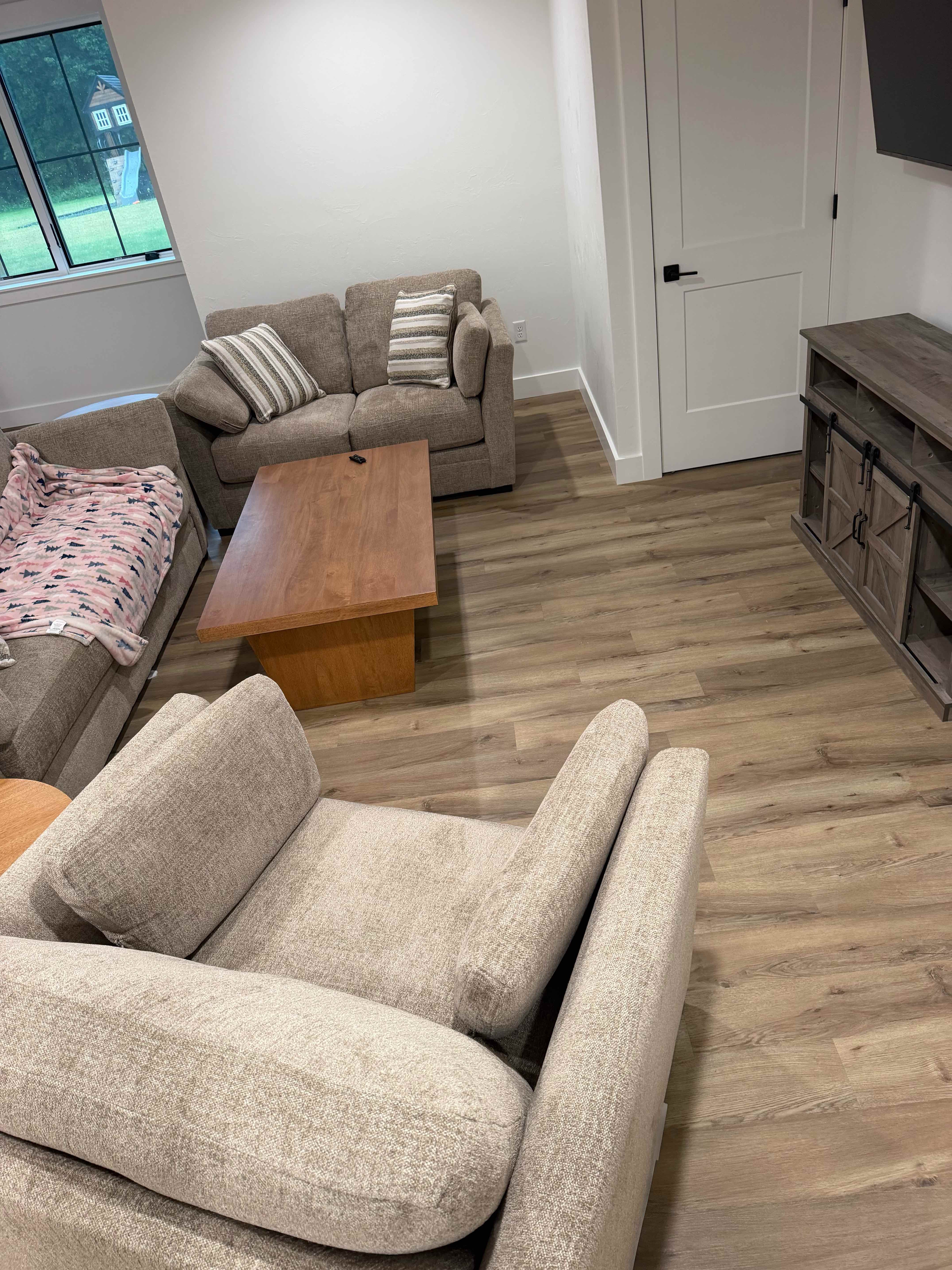 Wide-plank luxury vinyl flooring flowing through a finished basement living area installed by ARP Building Services in Mid-Michigan
