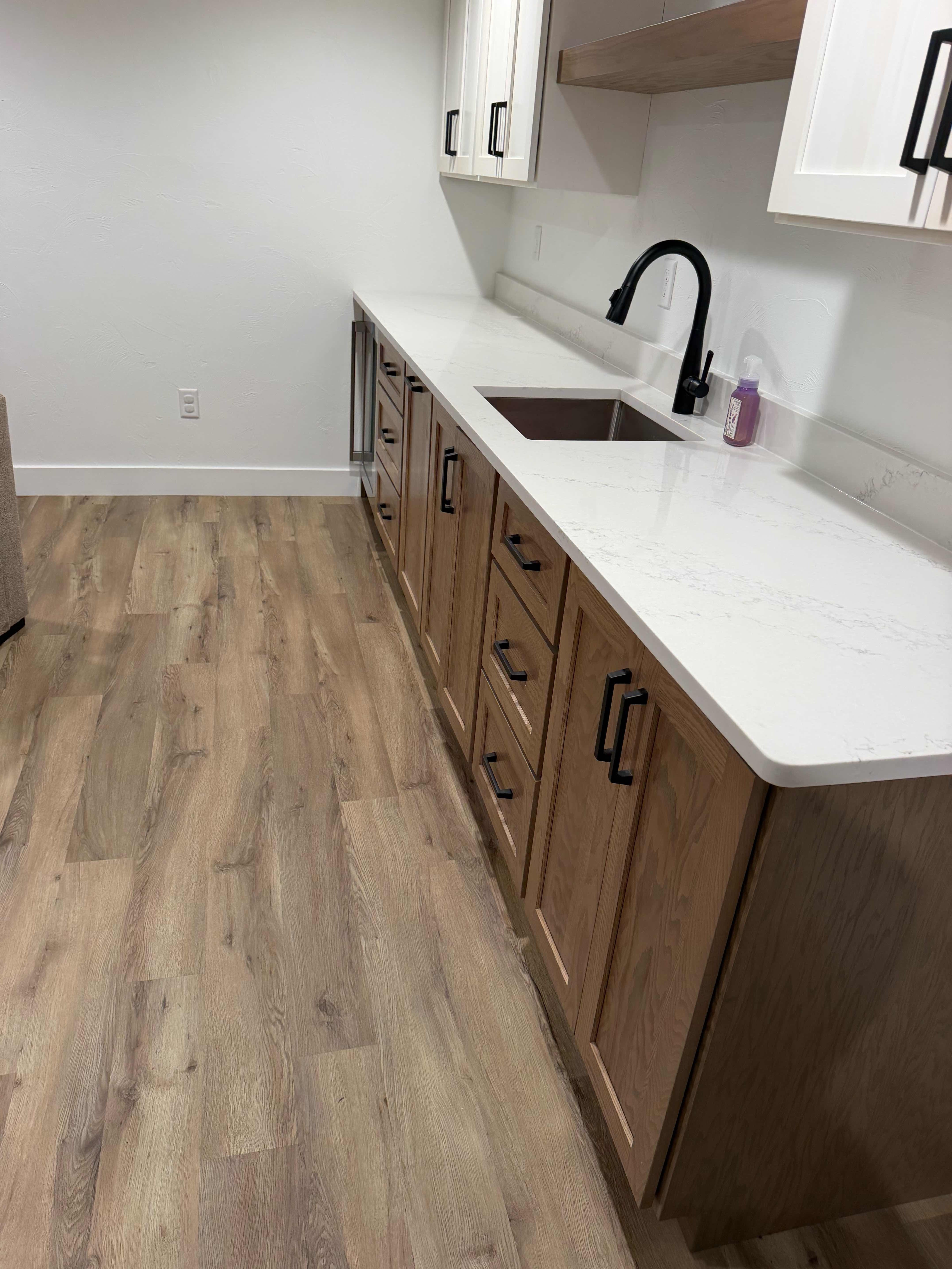 Custom wet bar with quartz waterfall counter in a finished Mid-Michigan basement