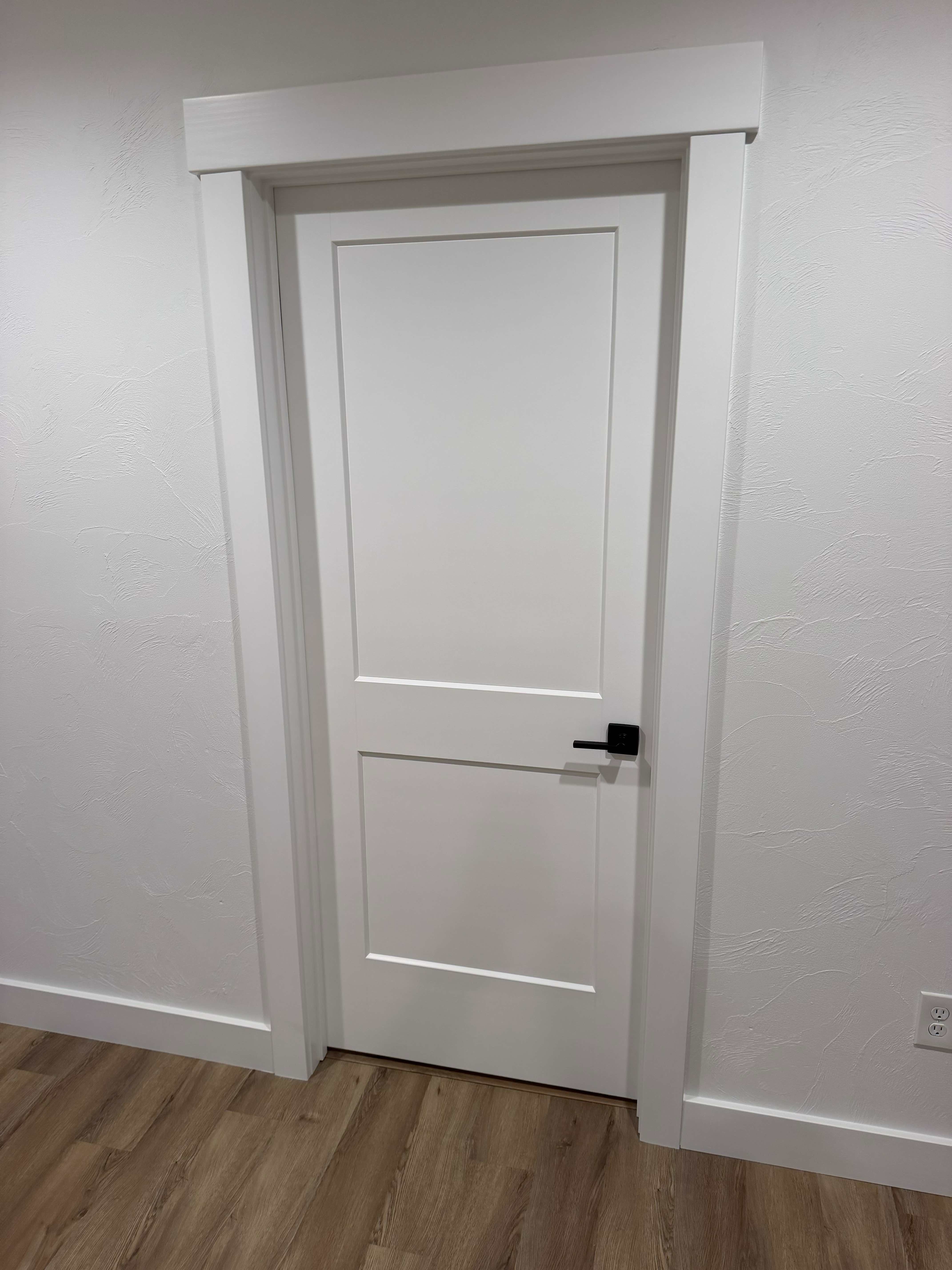 Craftsman-style white shaker interior door with wide casing and black lever hardware installed by ARP Building Services in Mid-Michigan